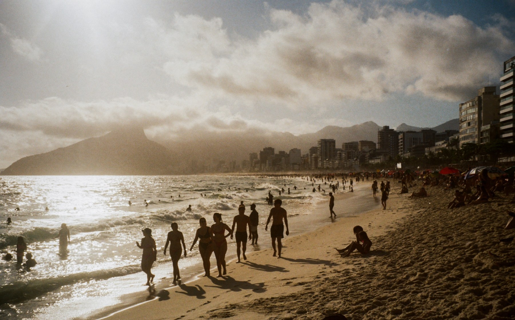 Golden late afternoon light over the shoreline at Ipanema with people walking along the water