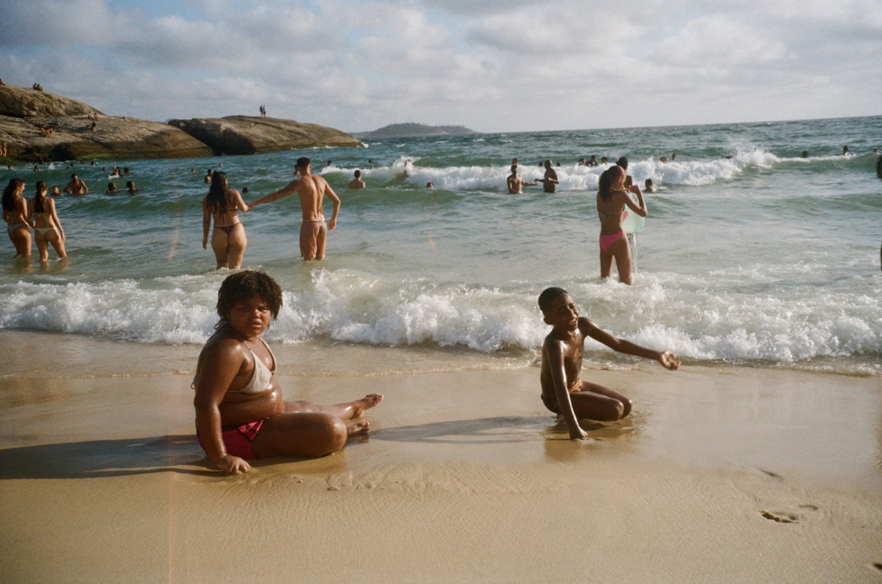 Two children sitting in the shallow water at the edge of the beach