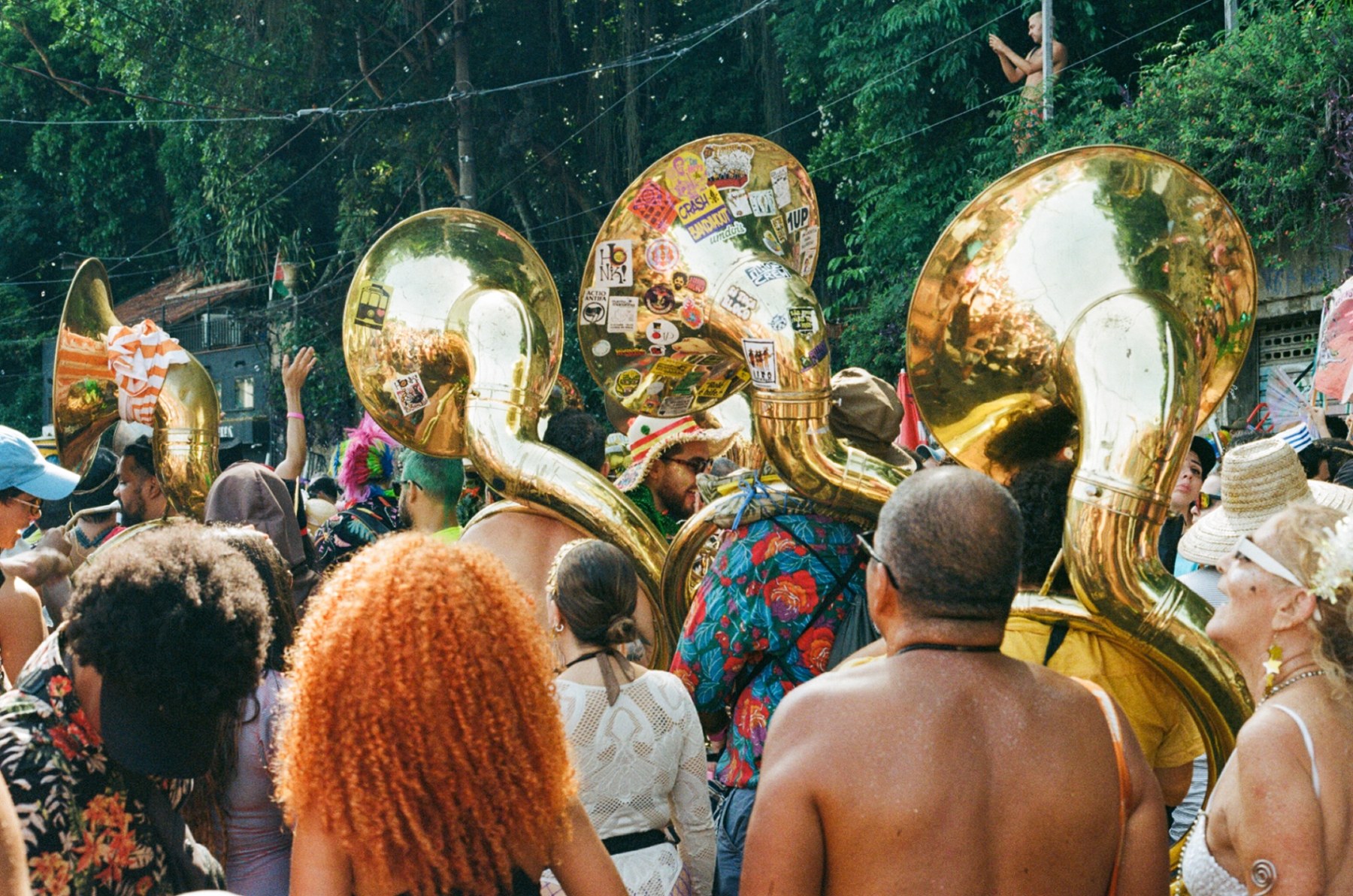 Sousaphones raised above a carnival street band moving through the crowd