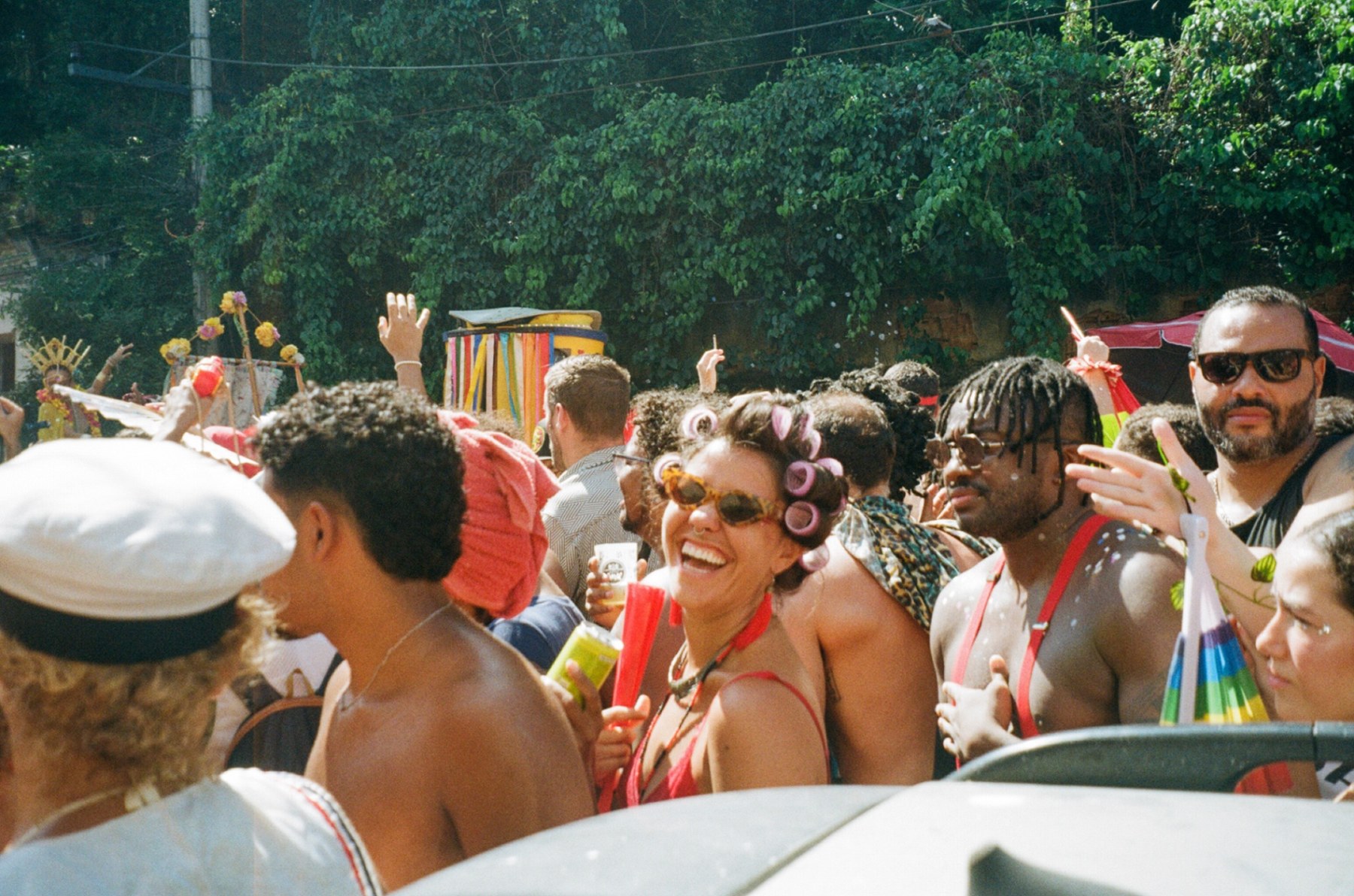 A woman in hair curlers laughing in a carnival crowd in the street