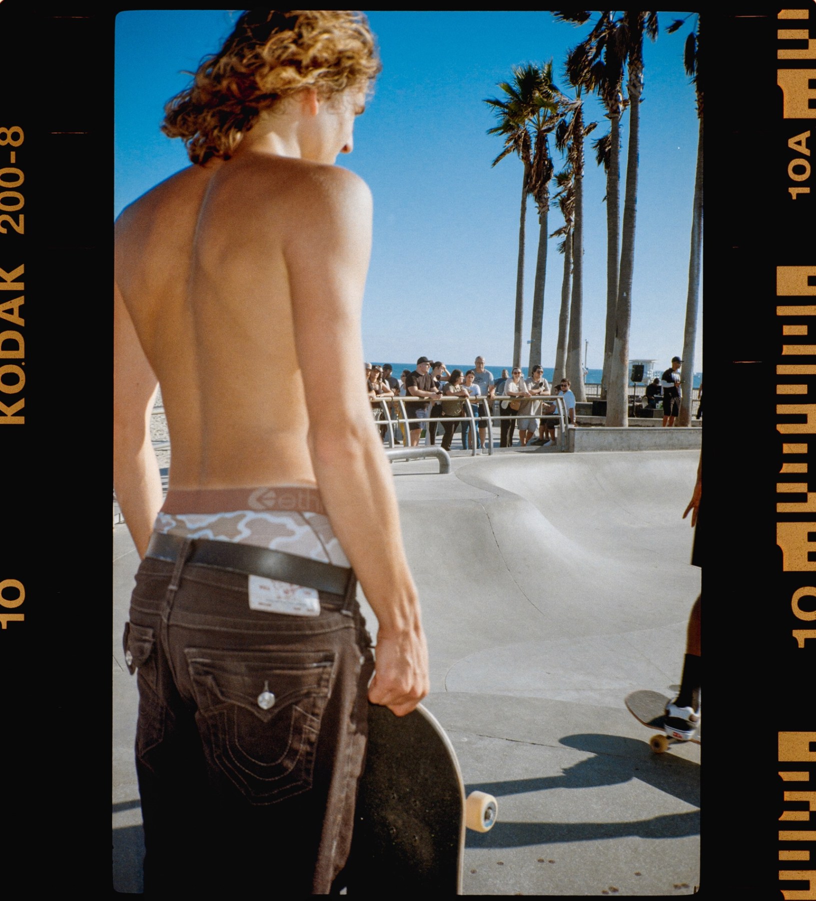 Skater standing at the edge of the Venice bowl, board in hand
