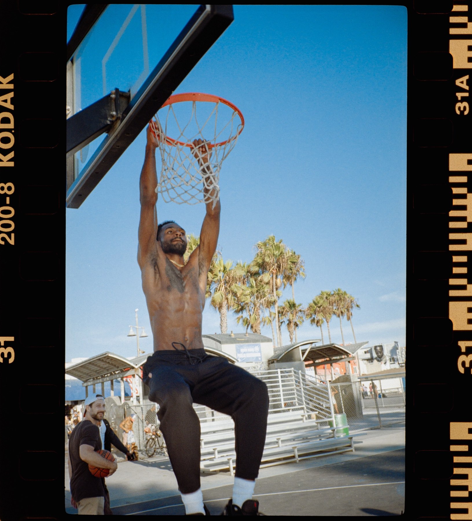 Basketball player hanging from the rim on the beach court